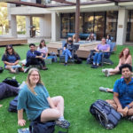 Daily Texan staffers sit in a circle outside for a meeting