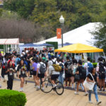 Many students walk along a tabling event along Speedway